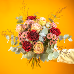 Small, round bouquet of pink santini, cream roses and burgundy carnations with eucalyptus