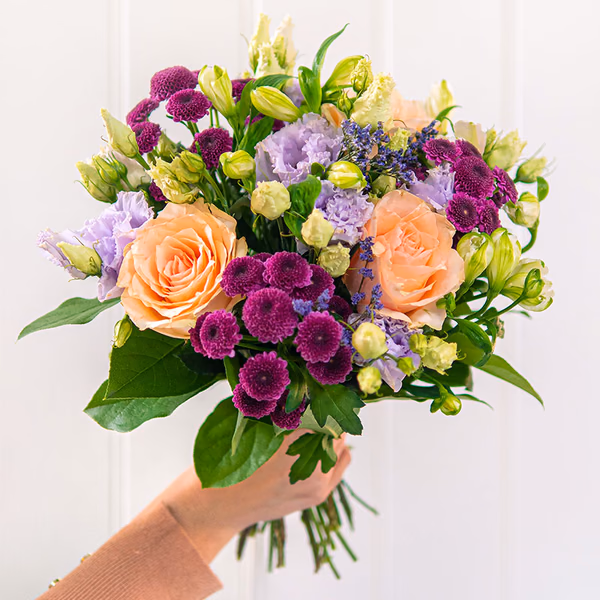 Small, round bouquet of apricot roses, purple santini, lilac lisianthus and cream alstroemeria