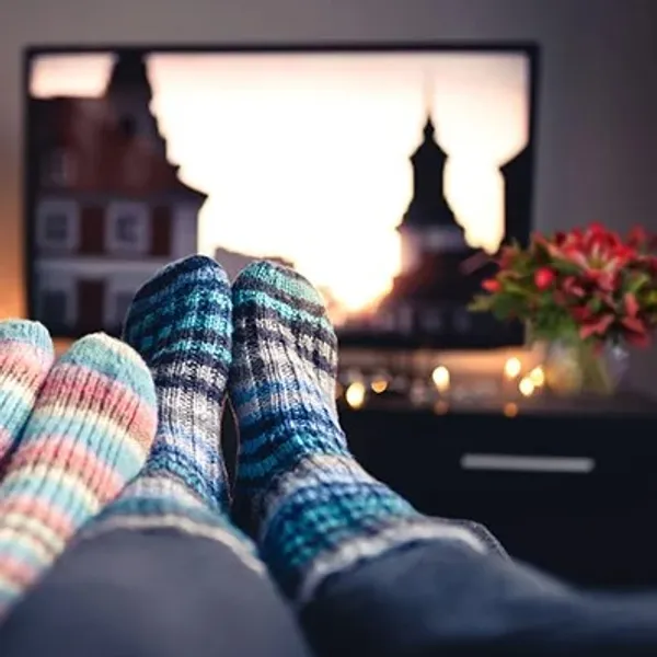 To par fødder i sokker med en rød buket i baggrunden.
