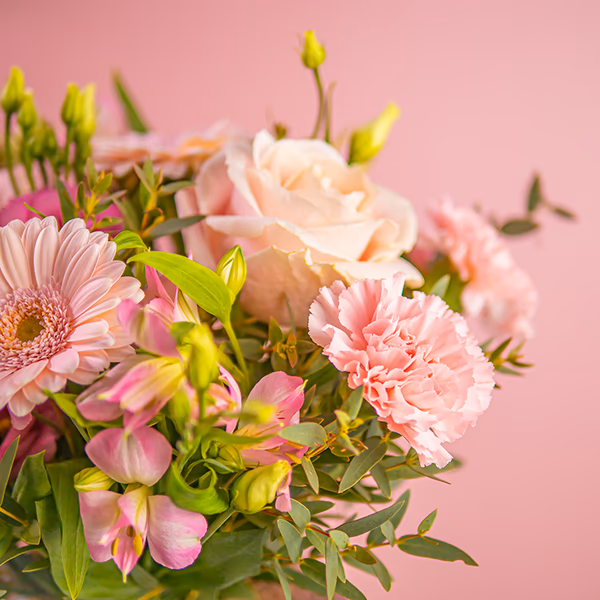 someone holding yellow and peach flowers