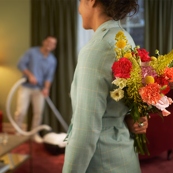 A woman holding a mixed bouquet behind her back
