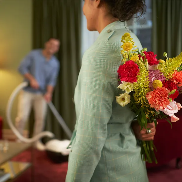 A woman holding a mixed bouquet behind her back