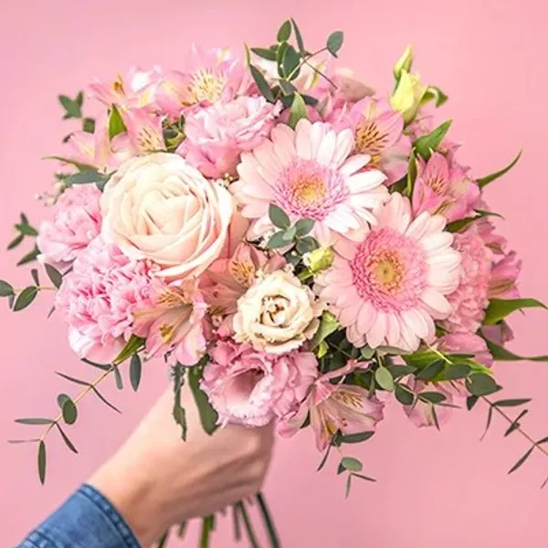 a hand holding a pink bouquet of flowers