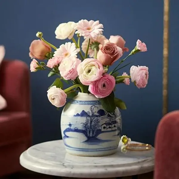 En bukett med rosa blomster i en hvit og blå vase