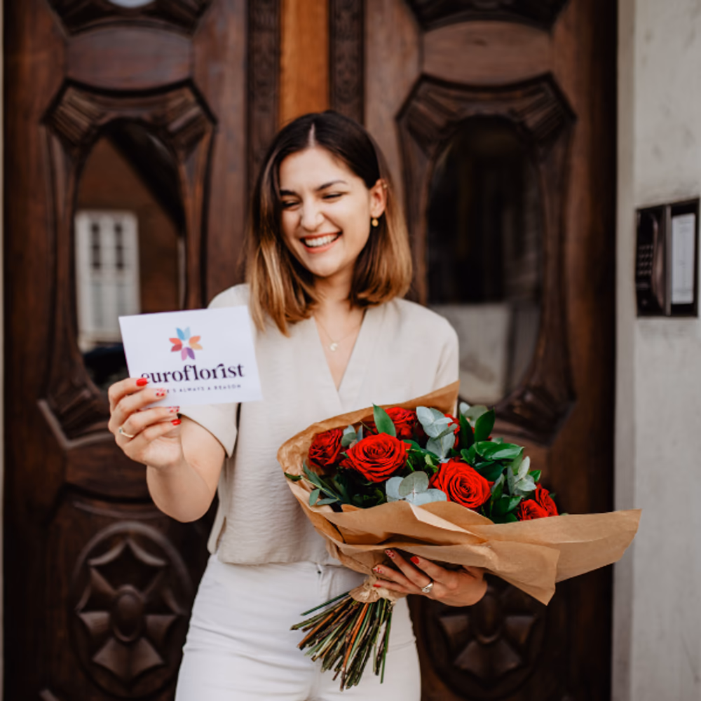 girl holding a bouquet of red roses and reading a card