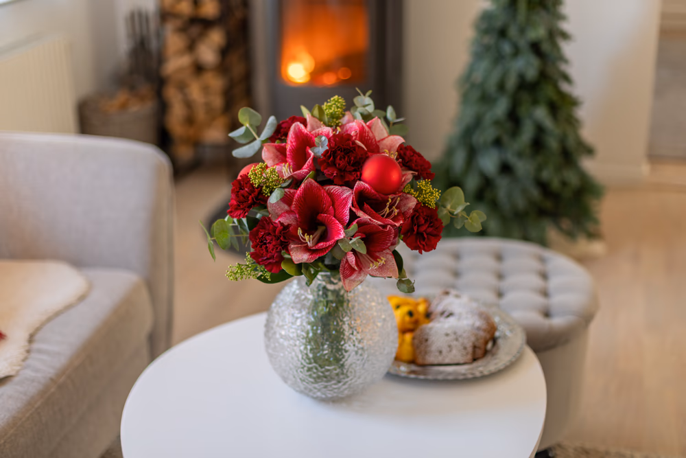 roter weihnachtsstrauss auf rundem couchtisch