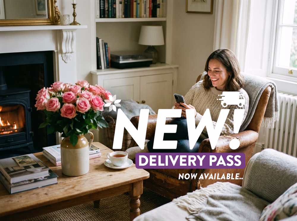 Woman sat in an armchair browsing on her phone, bouquet of pink roses on the table and text overlaid saying 'New delivery pass available'